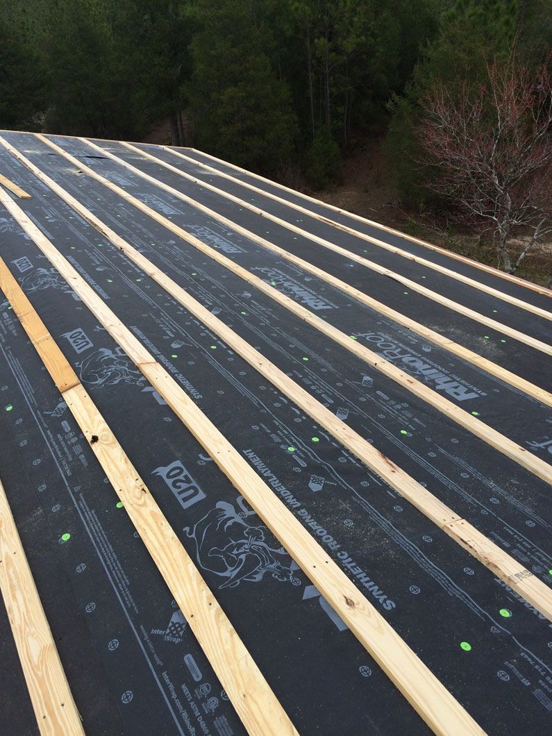A roof with wooden beams and a black roof covering.