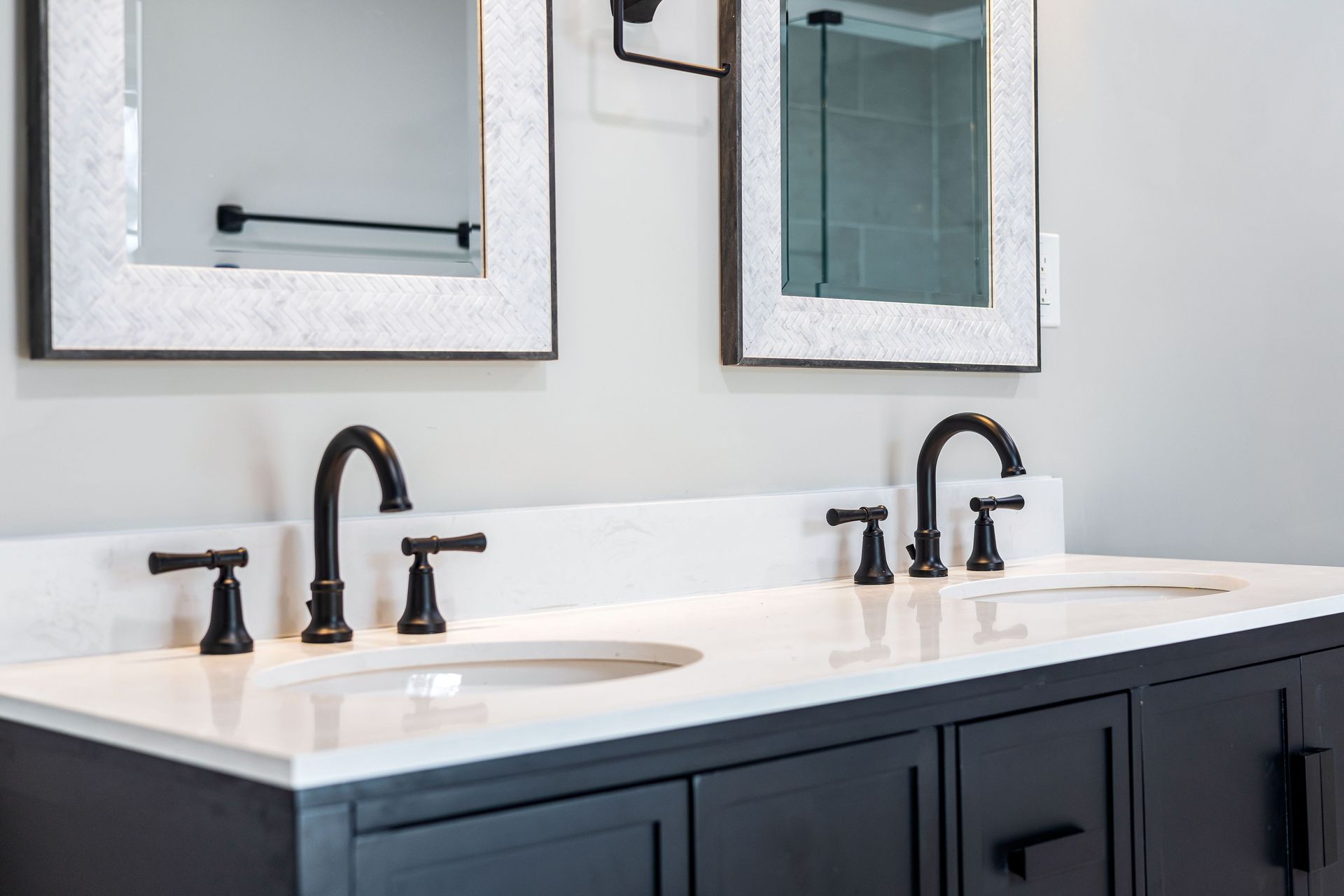 Modern bathroom vanity with double sinks, matte black faucets, and framed mirrors above a dark cabinet.
