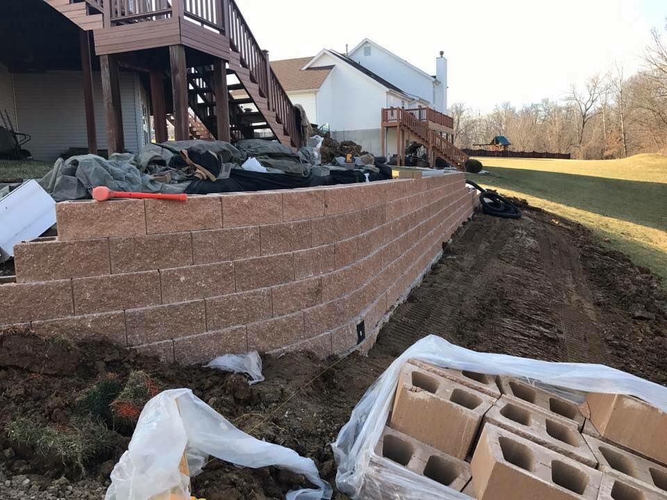 Red brick retaining wall under a wooden deck, with a grassy yard.