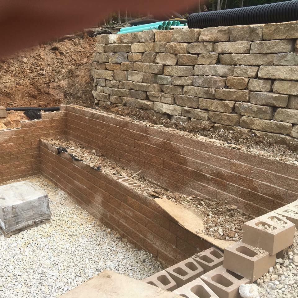 Construction site with tiered stone walls and brick layers, outdoor.