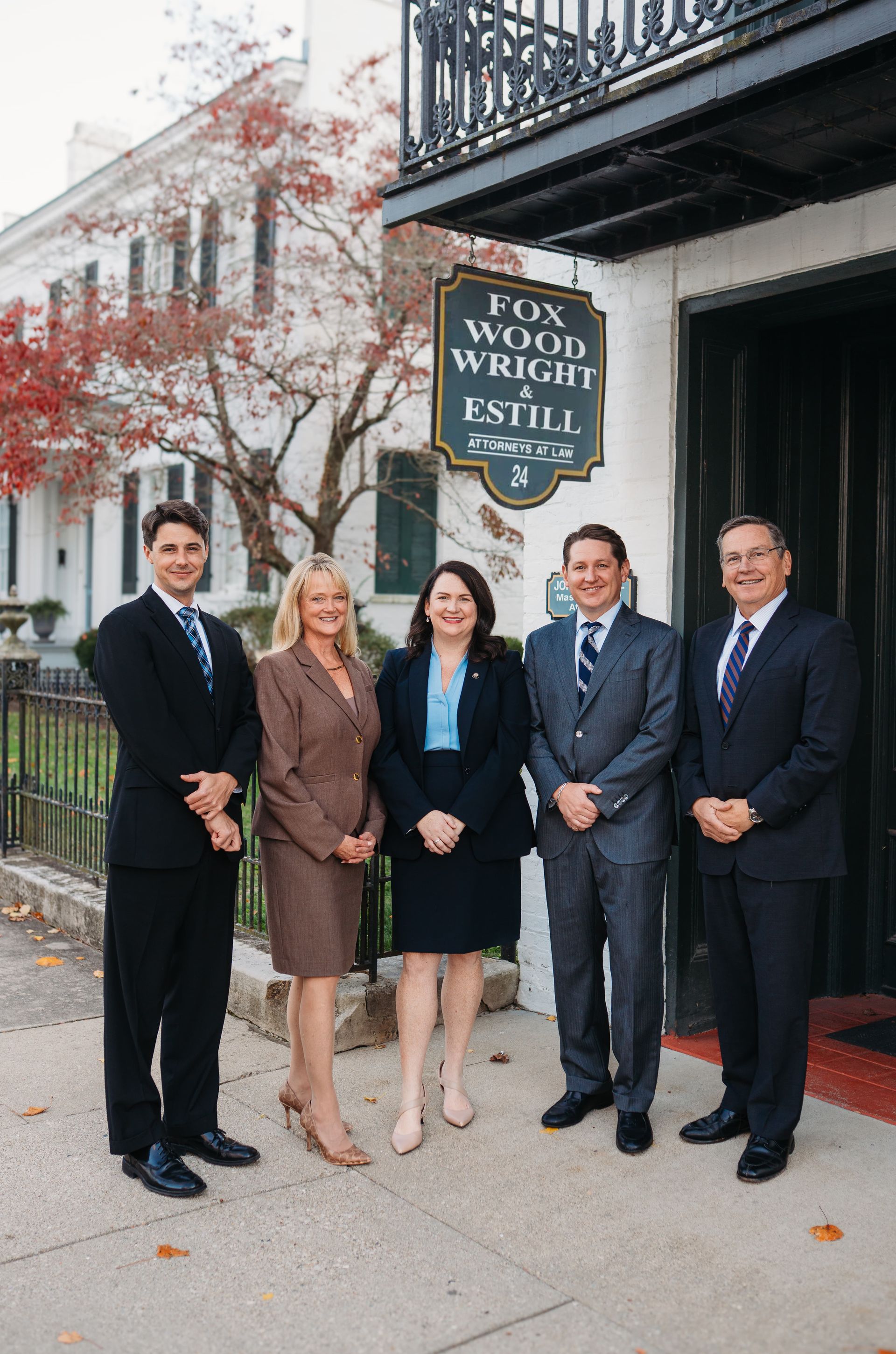 White multi-story building with black wrought-iron balcony and window trim.