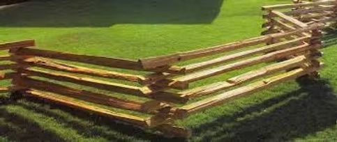 A zigzag wooden split-rail fence surrounds a vibrant green lawn.