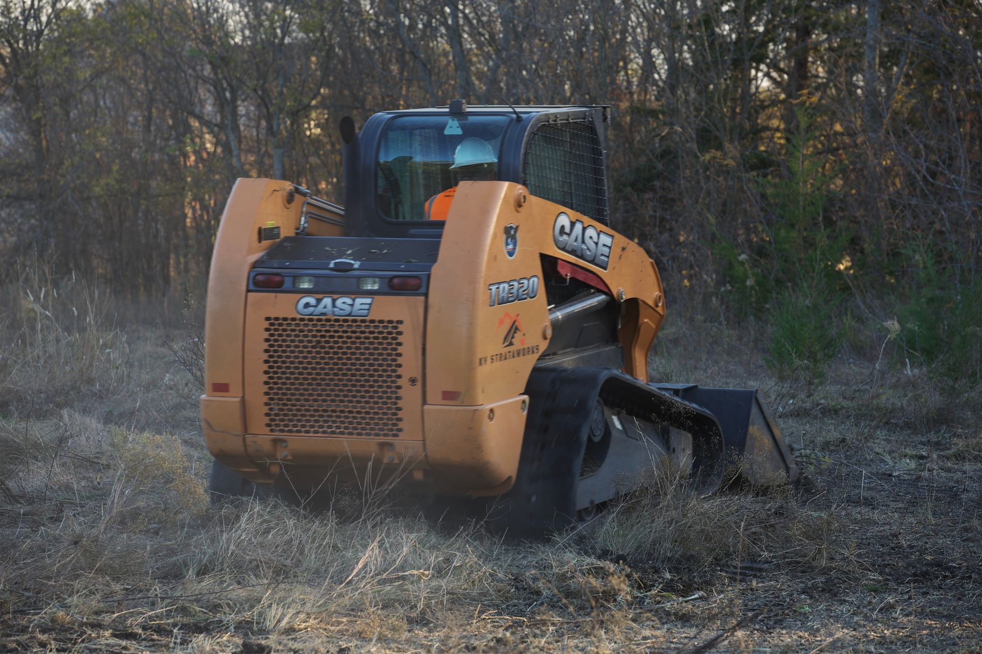 Skid steer performing grading work, smoothing and leveling soil for a new construction area.
