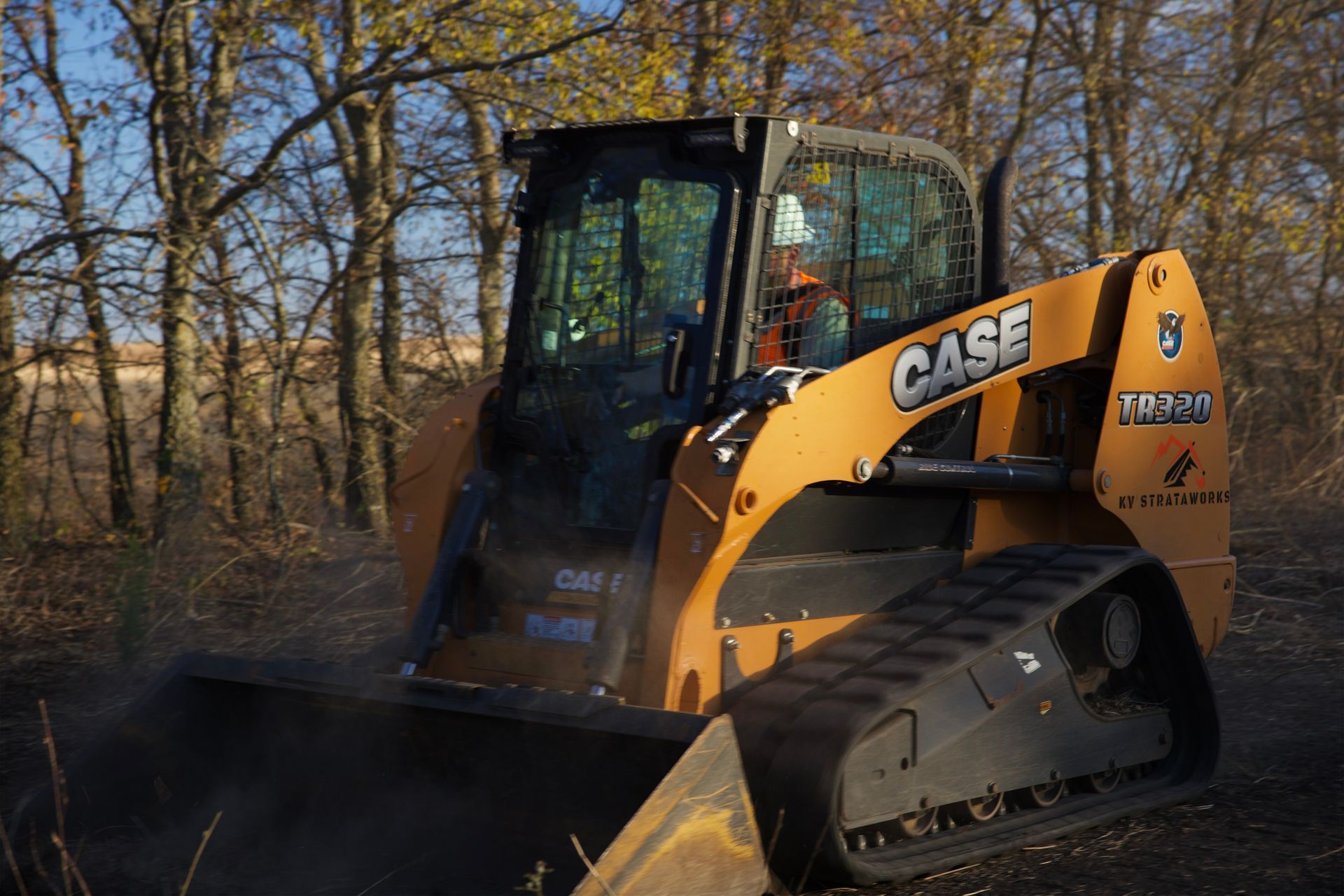 Skid steer performing grading work, smoothing and leveling soil for a new construction area.