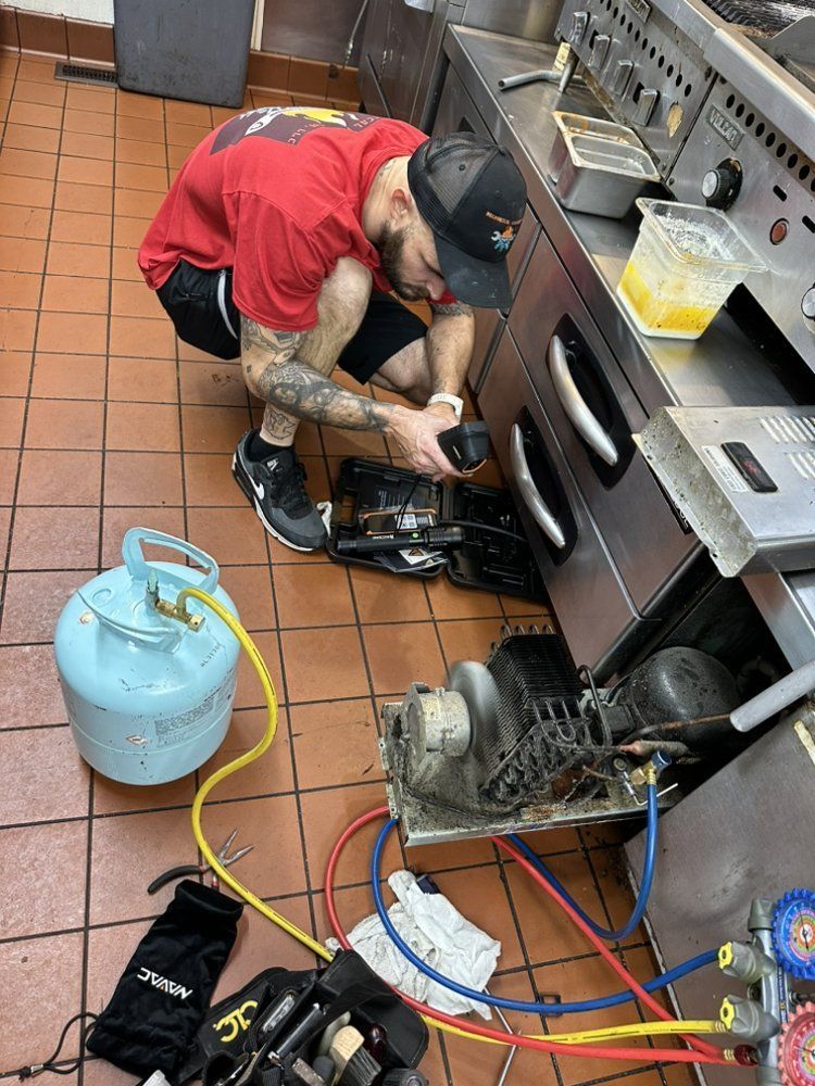 Technician performing commercial HVAC repair with gauges and tools in restaurant kitchen