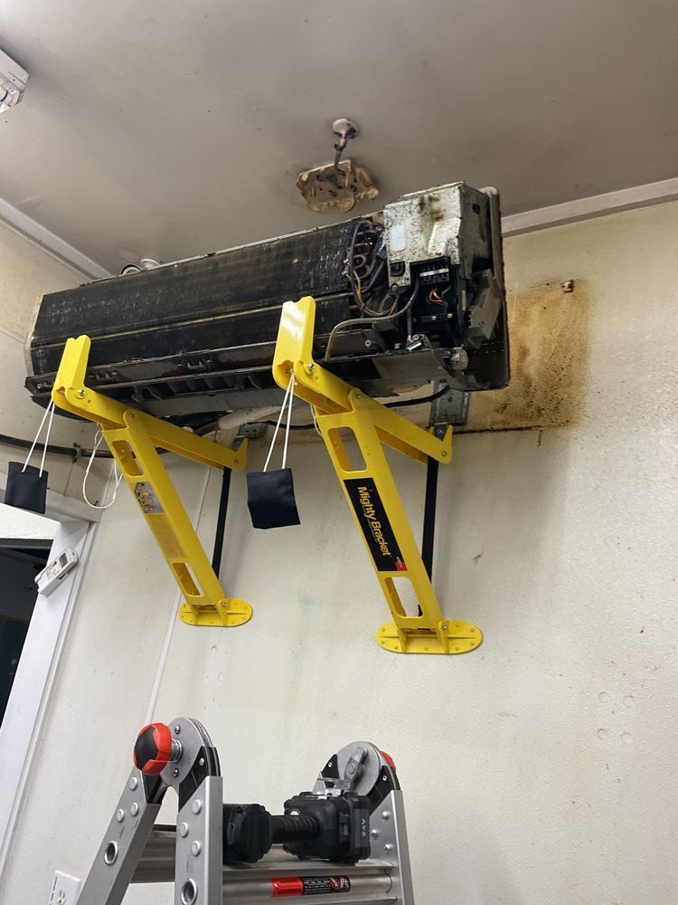 HVAC repair work on suspended indoor unit with brackets for commercial heating and cooling service