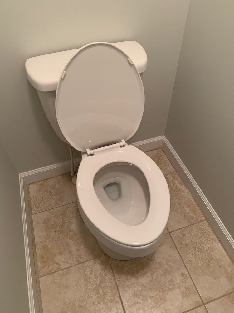 A white toilet is sitting in a corner of a bathroom.