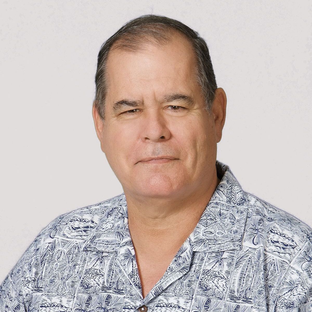 A man wearing a blue and white shirt is smiling for the camera.