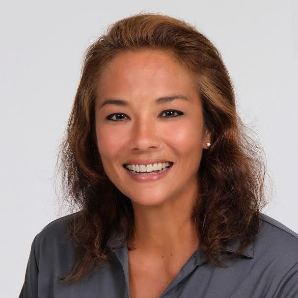 A woman in a grey shirt is smiling for the camera
