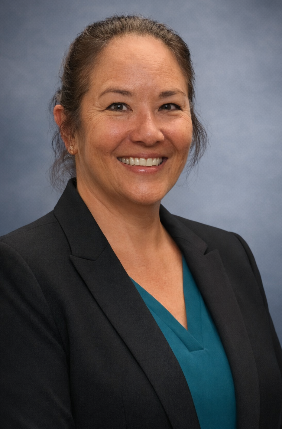 A woman in a grey shirt is smiling for the camera