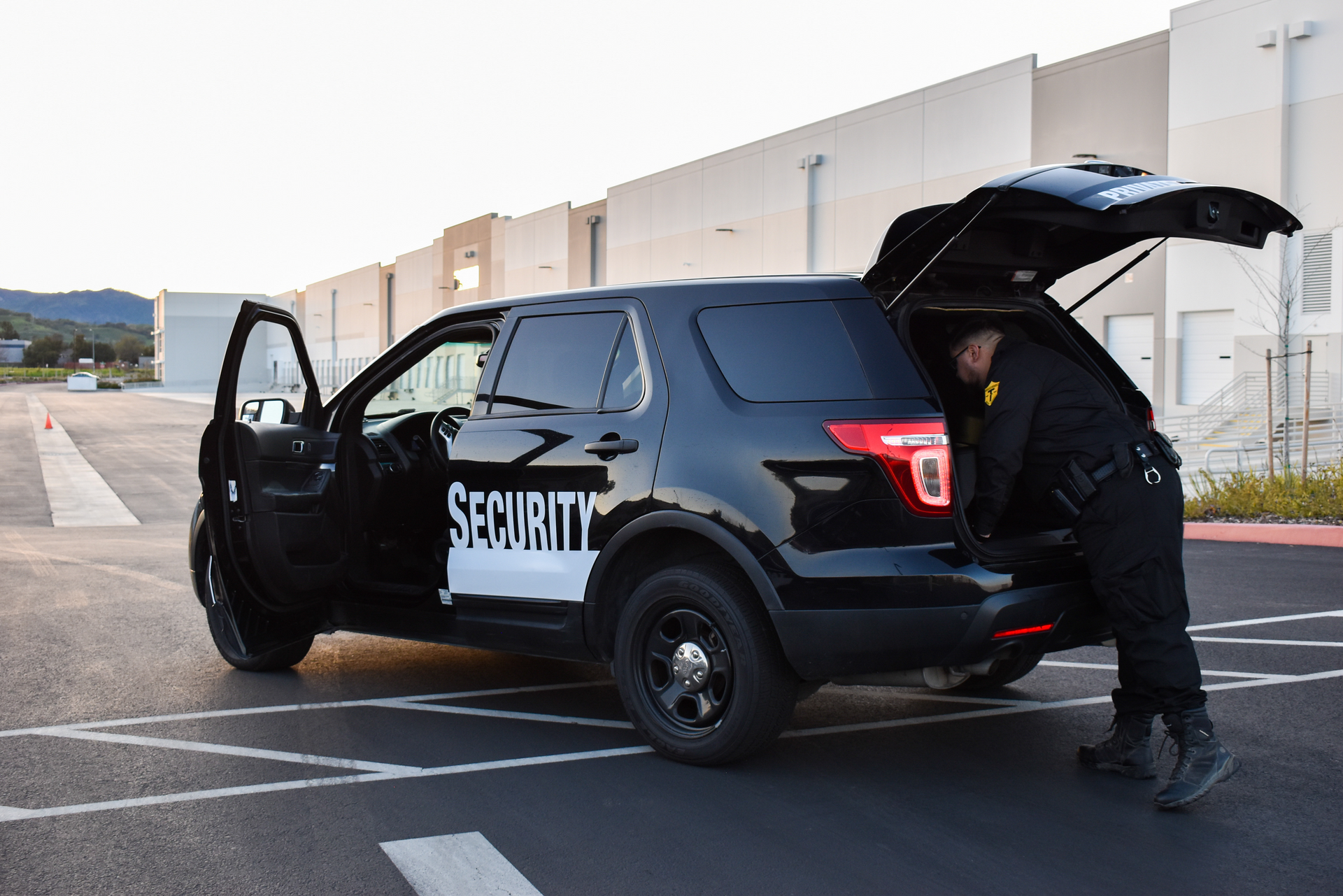 A security guard is opening the trunk of a security vehicle.