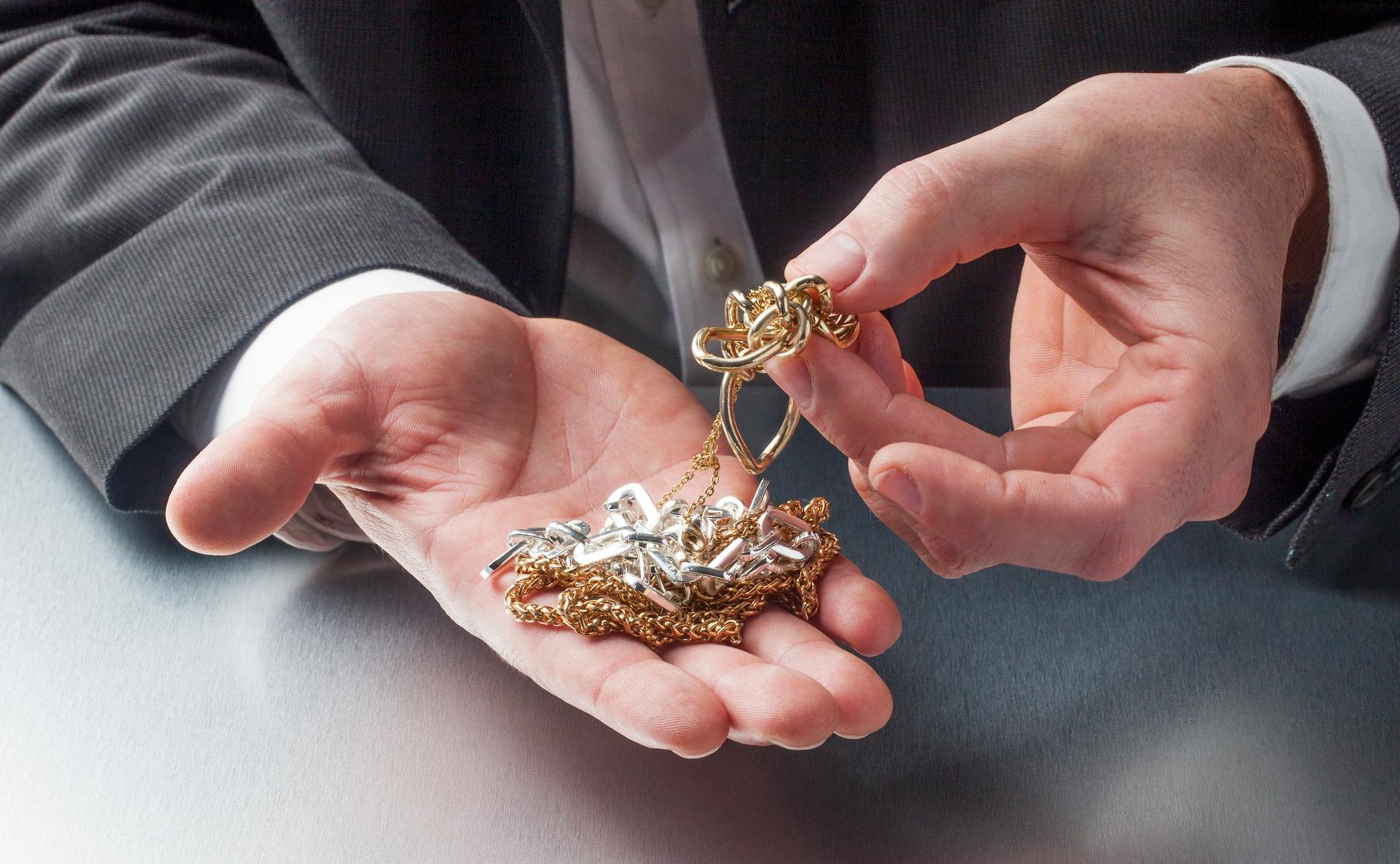 A man in a suit is holding a necklace in his hands