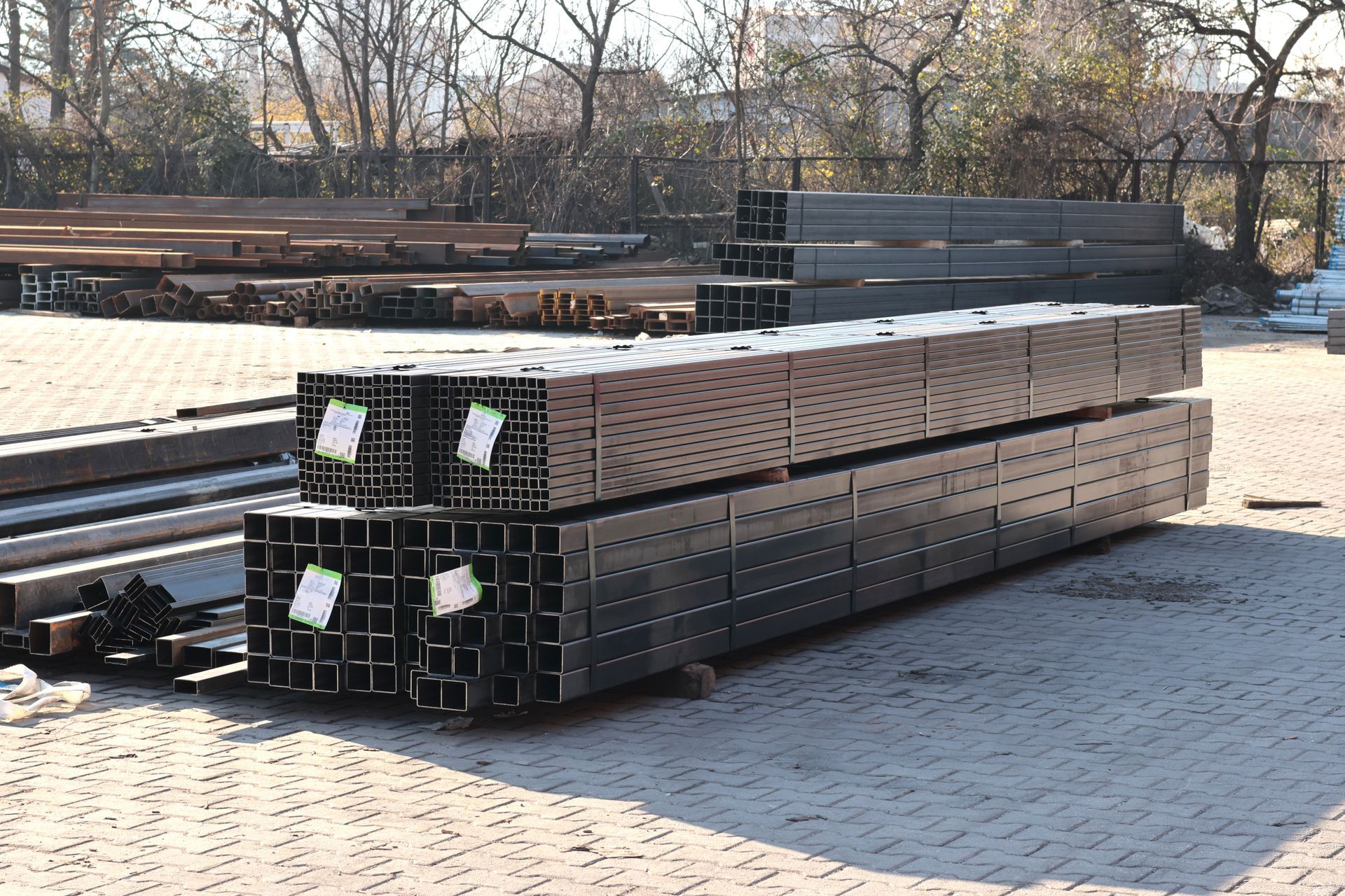 Stack of steel rectangular hollow sections placed on dirt ground at an outdoor construction site Stack of steel rectangular hollow sections placed on dirt ground at an outdoor construction site