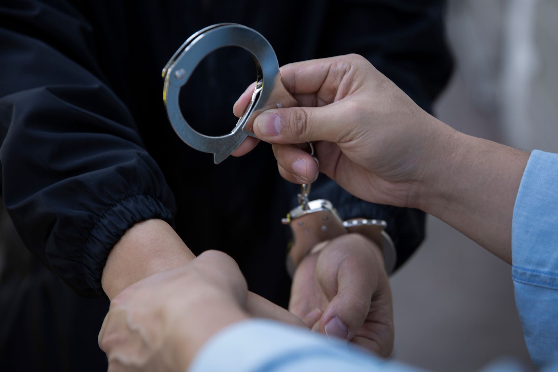 Person being handcuffed by another person.