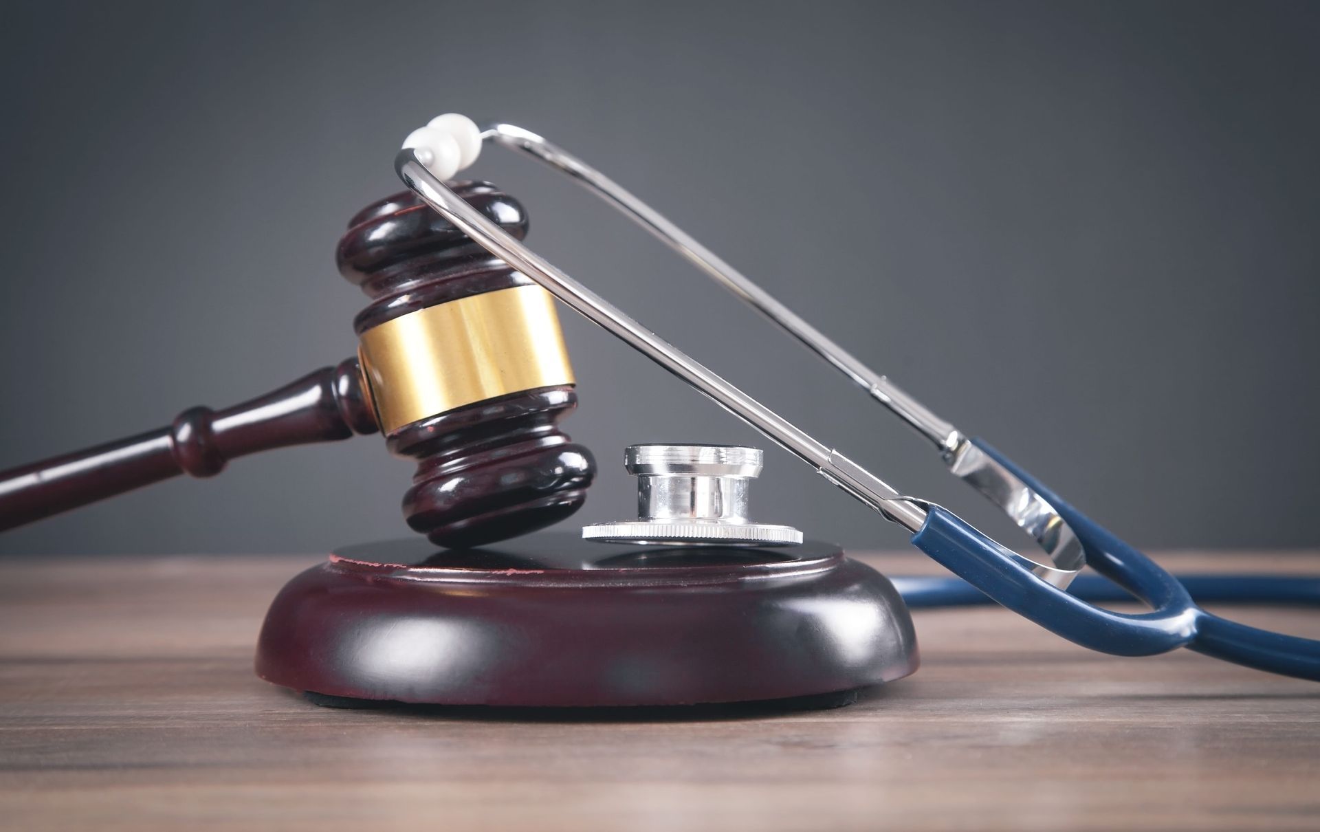 Judge’s gavel, stethoscope, and books on a desk, symbolizing legal or medical judgment