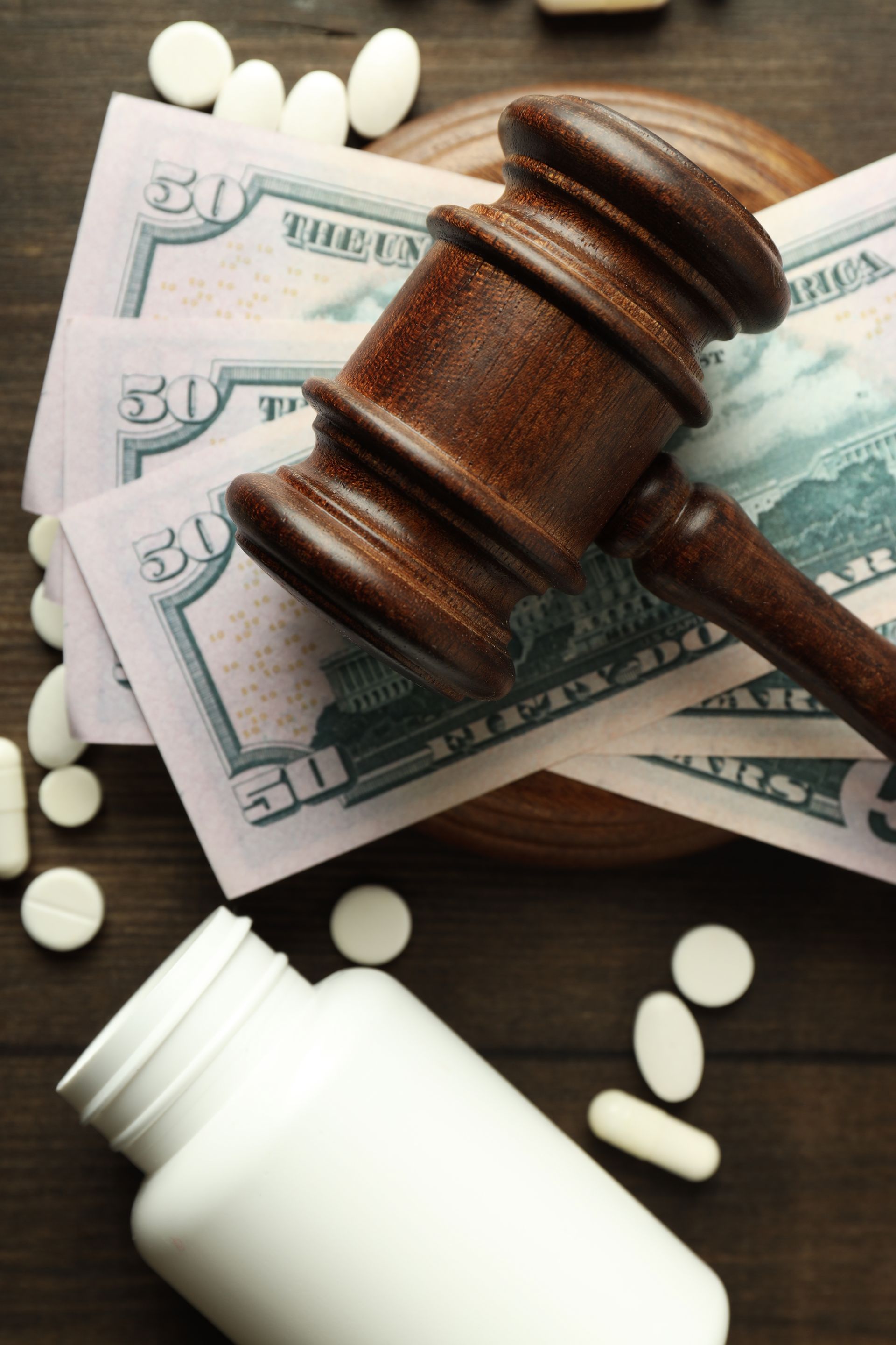 A judge 's gavel is sitting on top of a pile of money and pills.
