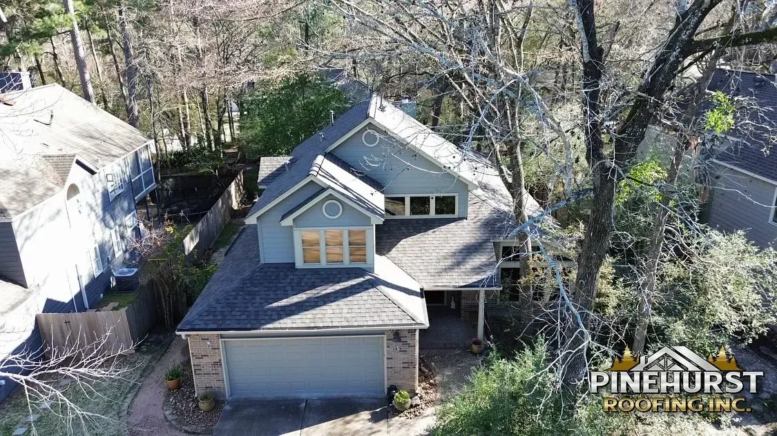 An aerial view of a house with a garage and trees in the background.