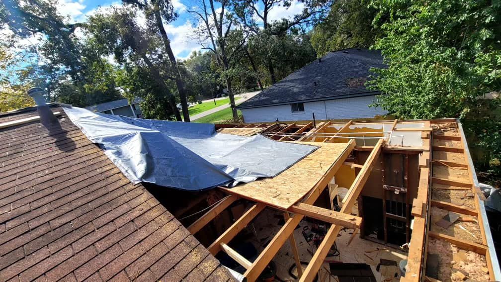 A roof of a house with a tarp on it.