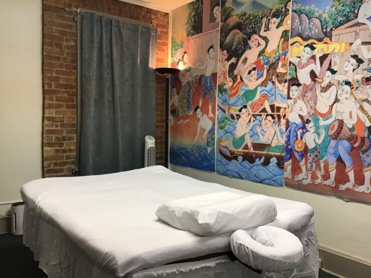 Massage room with a massage table, artwork on the wall, and a brick wall.