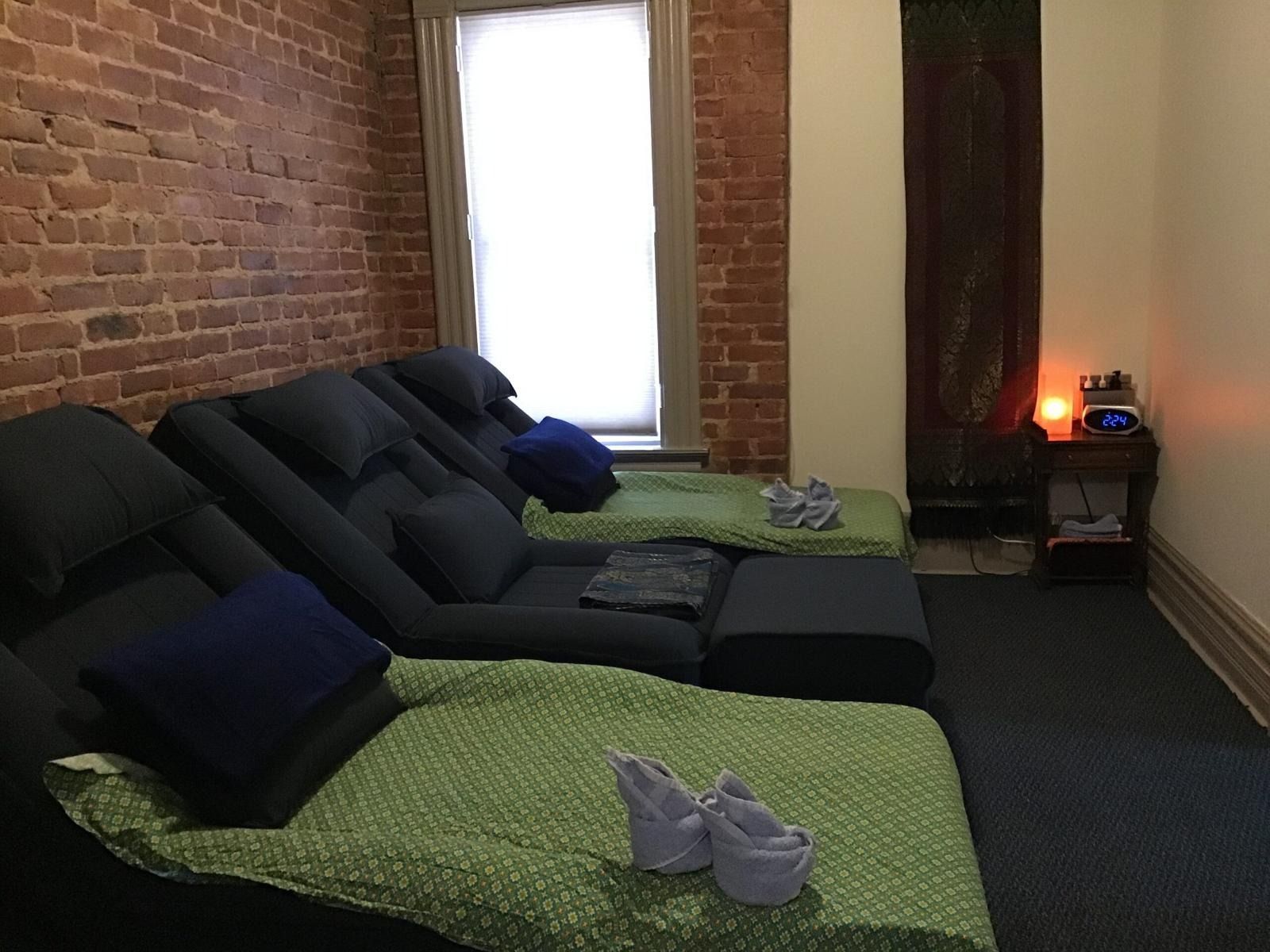 Relaxation room with reclining couches, brick wall, window, and footstools.
