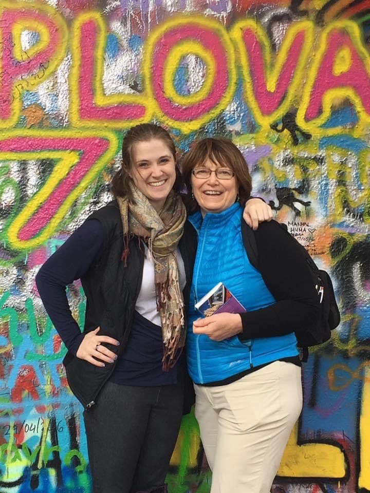 Two women are posing for a picture in front of a graffiti wall.