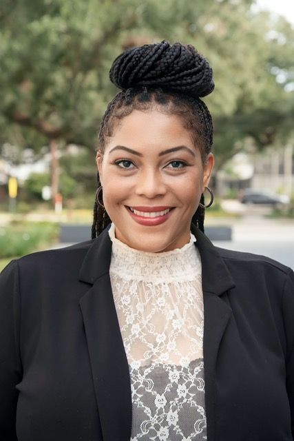 A woman in a black jacket and white top is smiling for the camera.