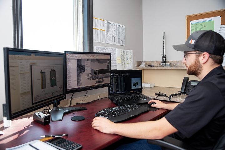 Un homme est assis à un bureau et travaille sur un ordinateur.