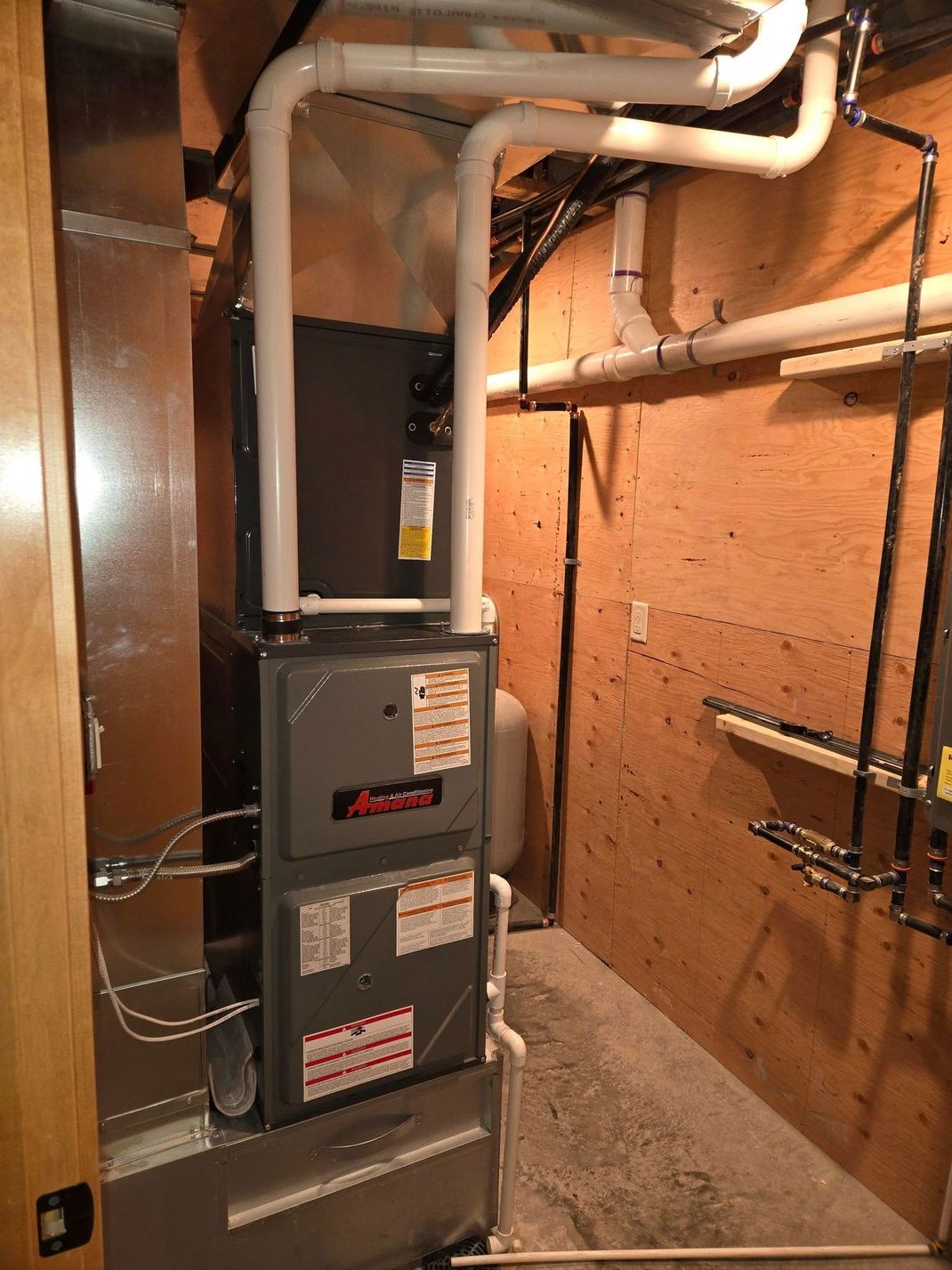 A room with a furnace and pipes hanging from the ceiling.
