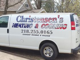 A christensen 's heating and cooling van is parked in front of a house
