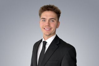 A young man in a suit and tie is smiling for the camera.