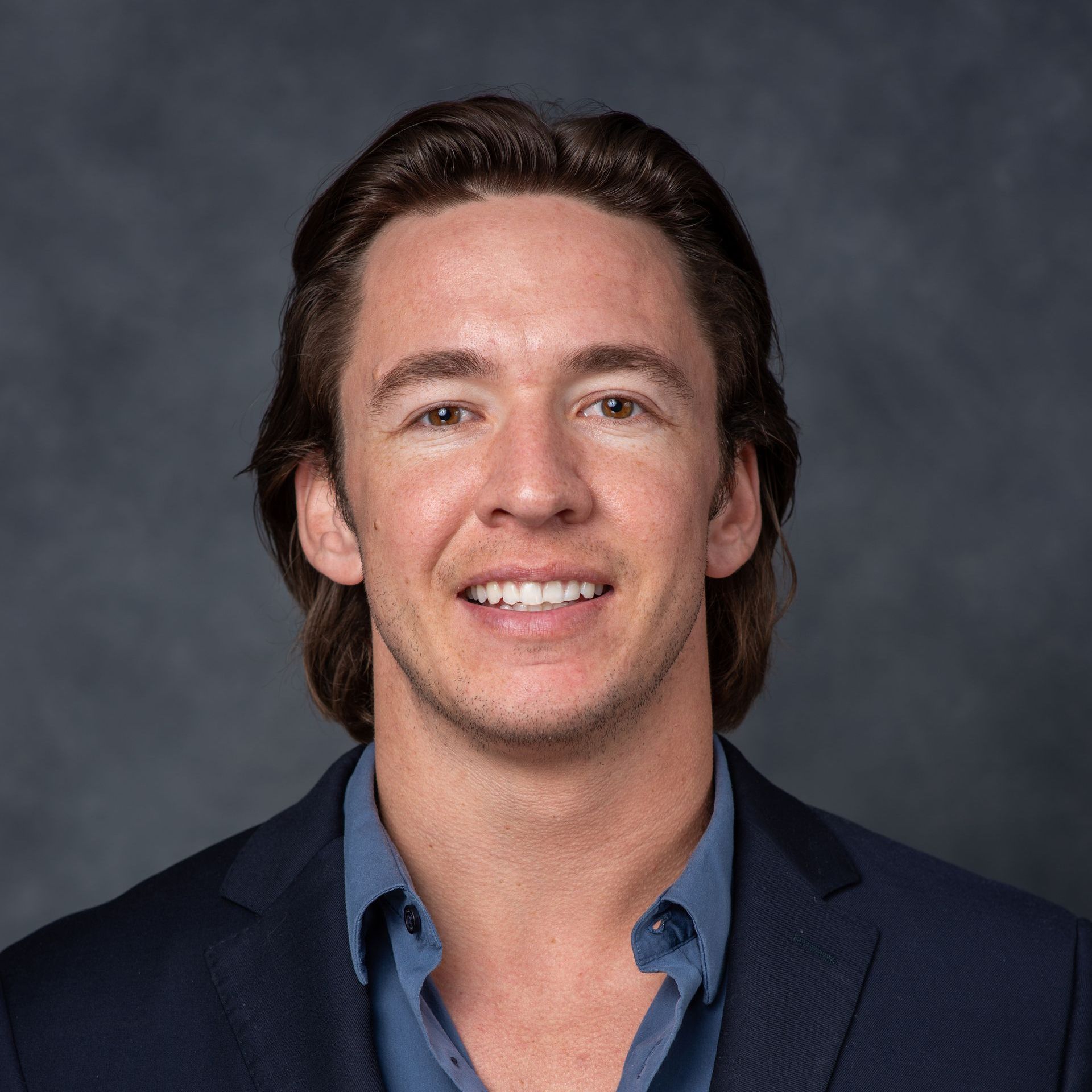 A man in a suit and blue shirt is smiling for the camera.