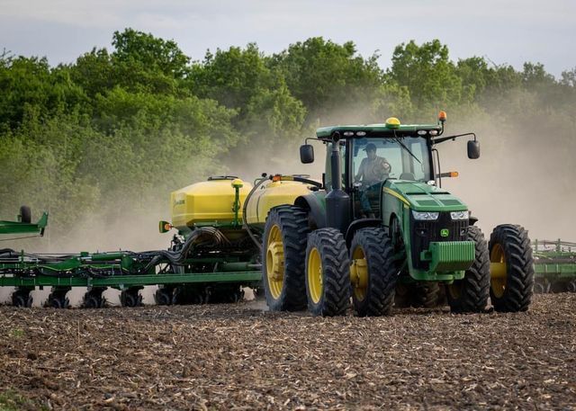 An aerial view of a tractor spraying a field of wheat.