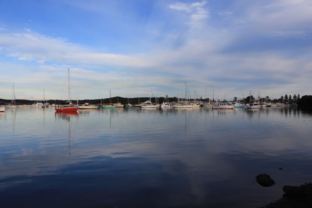 A Row Of Boats Are Docked In A Harbor On A Cloudy Day  — Castledine's Truck Painting & Repairs in Lake Macquarie, NSW