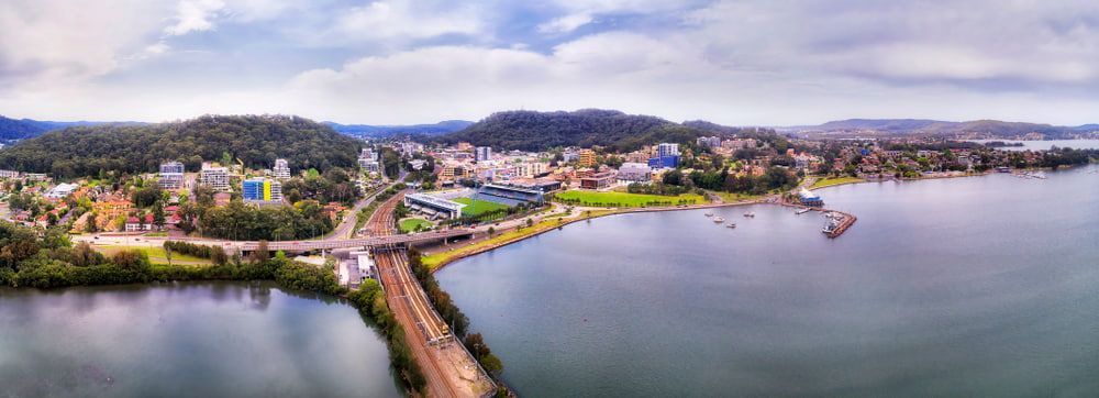 An Aerial View Of A Bridge Over A Body Of Water With A City In The Background  — Castledine's Truck Painting & Repairs in Gosford, NSW