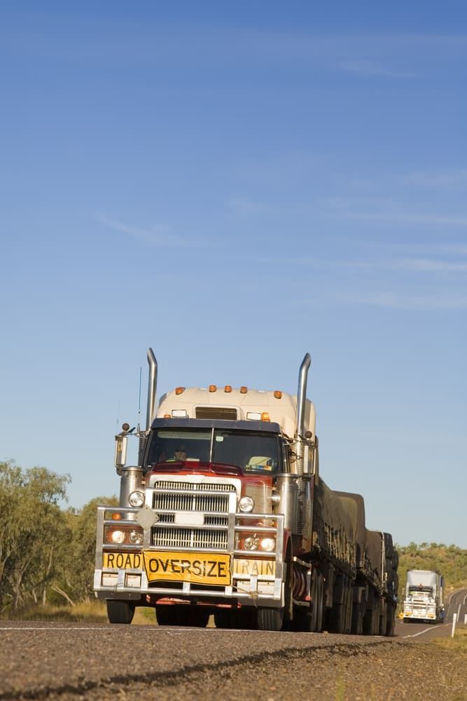 A Large Semi Truck Is Driving Down A Dirt Road — Castledine's Truck Painting & Repairs in Gosford, NSW