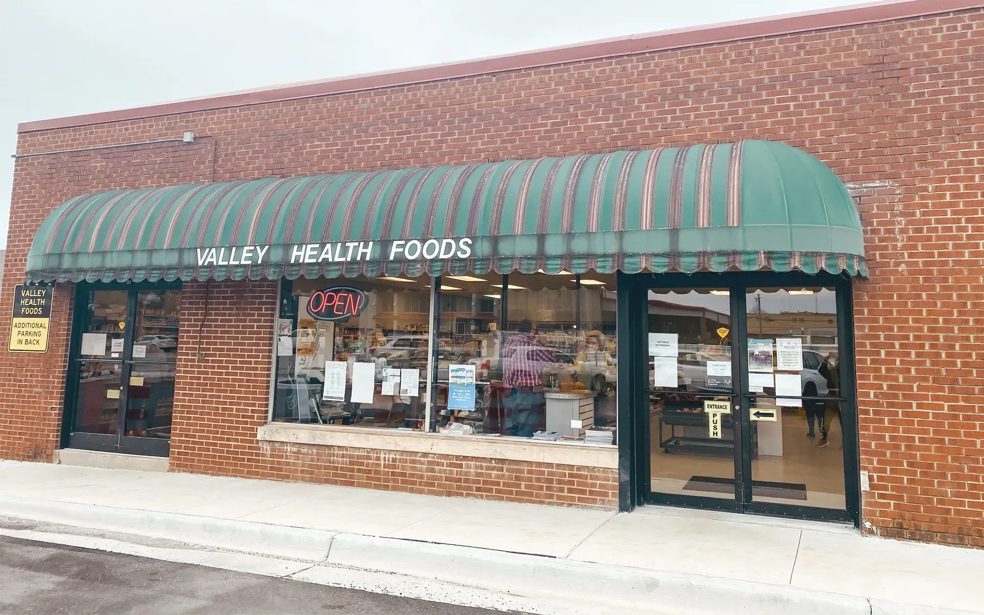 Valley Health Foods store with green awning, brick exterior, and glass windows.