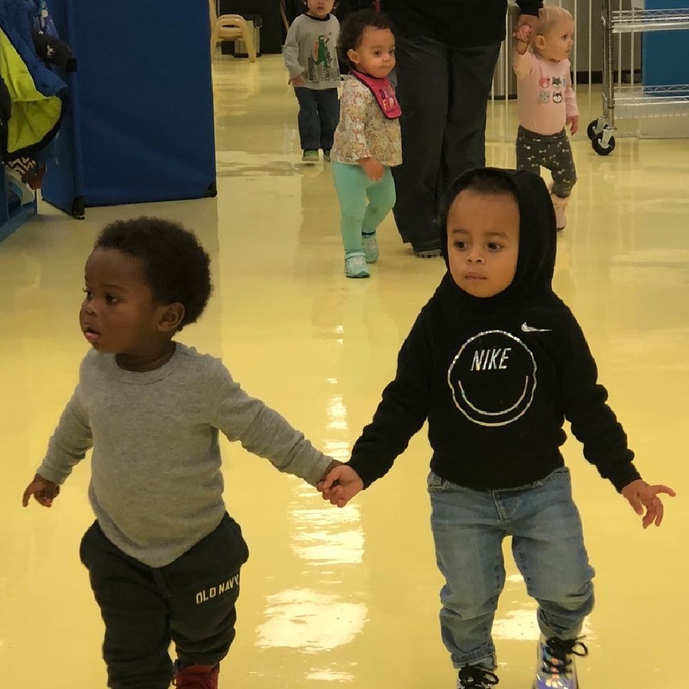 two toddlers holding hands at the learning center