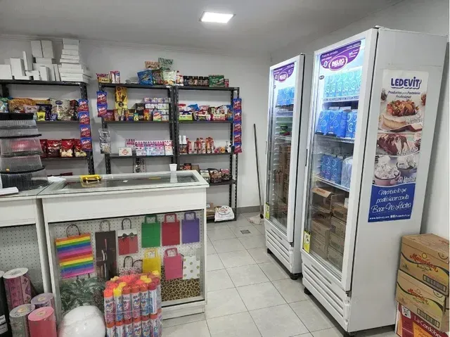 Pasillo de tienda de conveniencia con bebidas refrigeradas, refrigerios y una caja registradora.