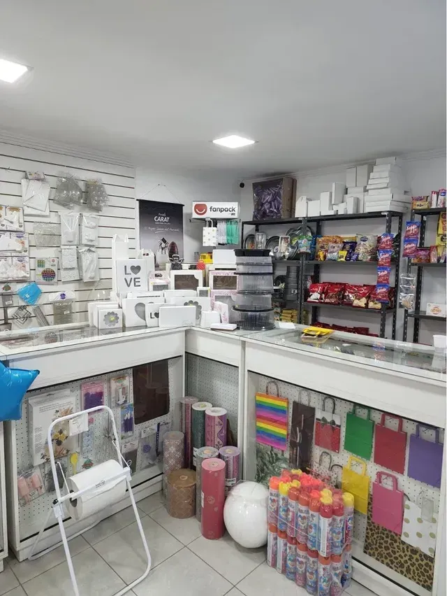 Pequeño mostrador con tarjetas de felicitación, papel de regalo y artículos de papelería variados en estantes y expositores.