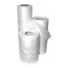 Bolsas de plástico blancas apiladas con etiquetas verdes impresas y de tamaño sobre un fondo liso.