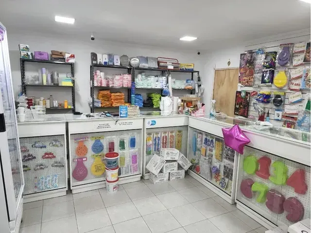 Interior luminoso de una tienda minorista con bolsas coloridas, estantes y productos empaquetados sobre mostradores blancos.