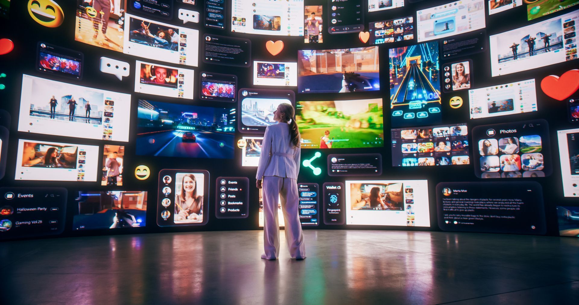 Woman stands in front of a large screen showing all kind of content, emojis, social media icons, video games, and text. 