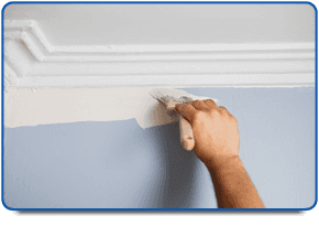 Hand painting a blue wall with white paint