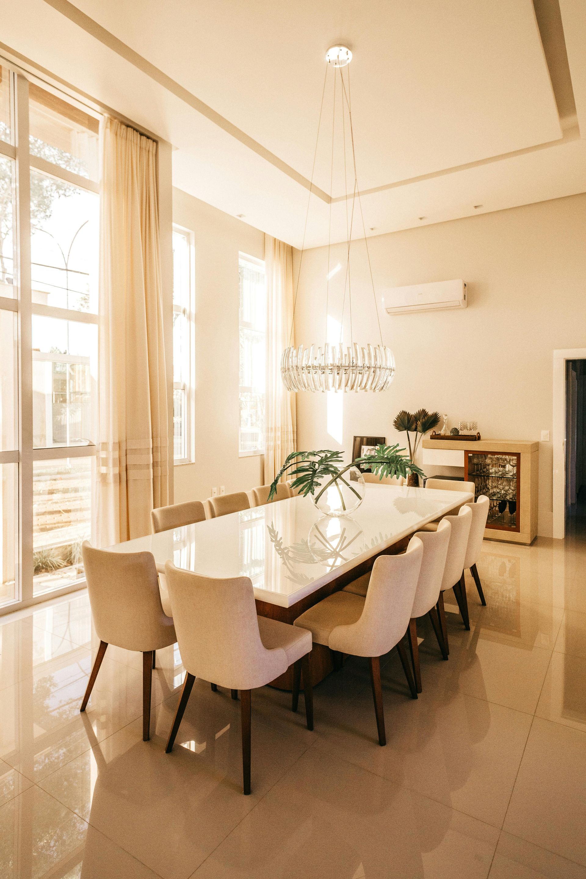 A dining room with a long table and chairs and a chandelier.
