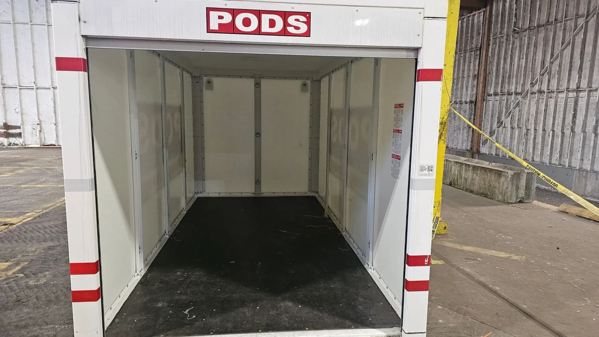 An empty pods trailer is parked in front of a building.