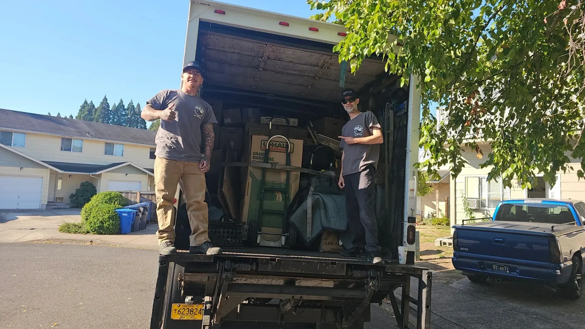 Two men are standing in the back of a moving truck.