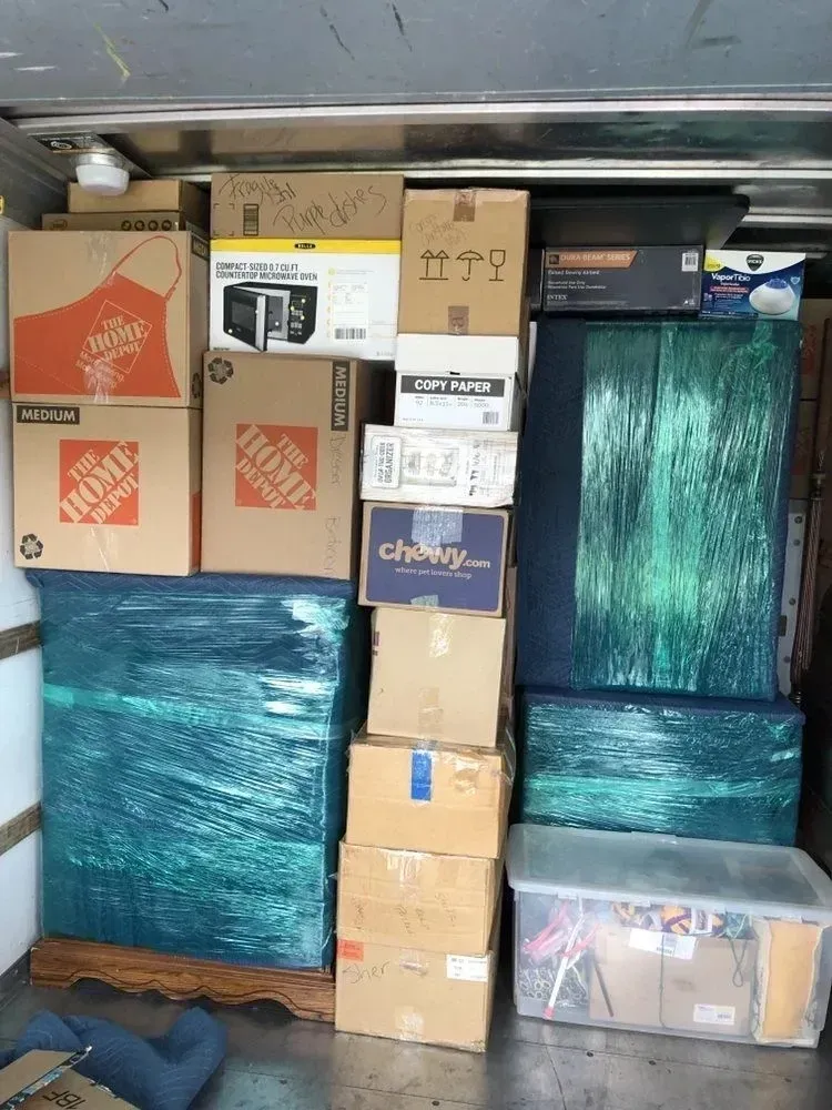 A stack of boxes wrapped in plastic is sitting in the back of a truck.