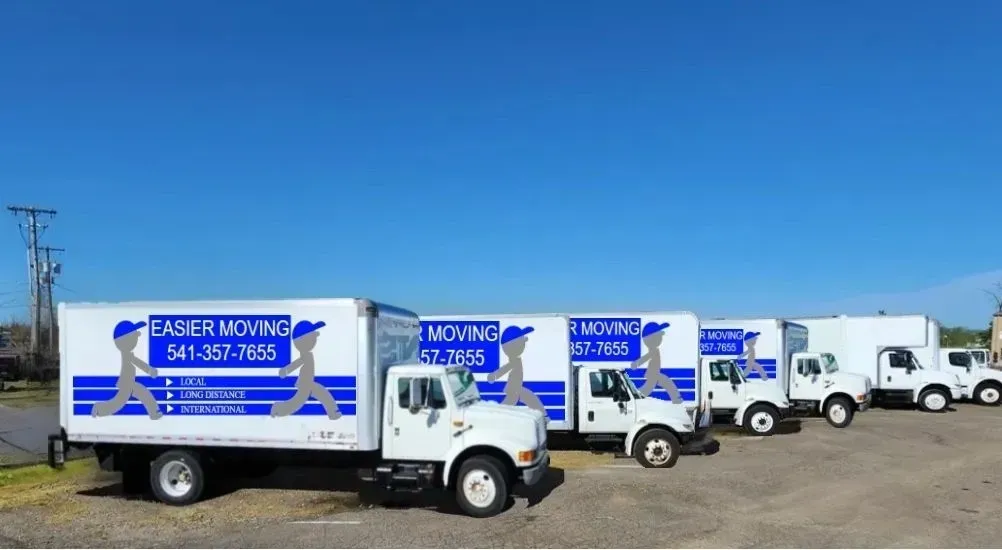 A row of moving trucks are parked in a parking lot.