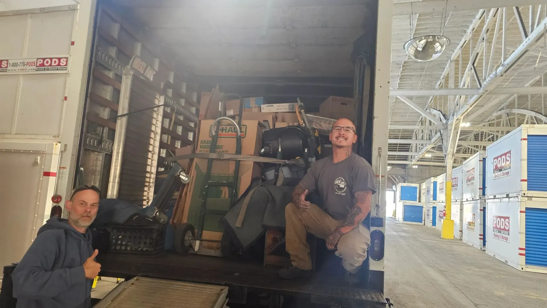 Two men are sitting in the back of a truck.