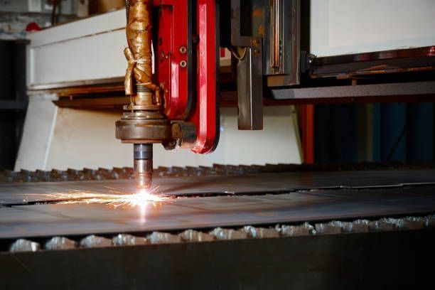 Laser cutter cutting metal sheet, sparks visible. Close-up on industrial machine in action.